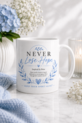White gloss ceramic mug featuring the Never Lose Hope design with blue watercolour botanical wreath and the message "Inspired by Reiss" from the Keep Your Spirit Alive® collection.